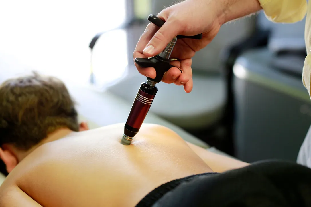 Hand using Activator Adjusting Instrument on patient's back during chiropractic treatment at Elevated Chiropractic in Broomfield, CO.