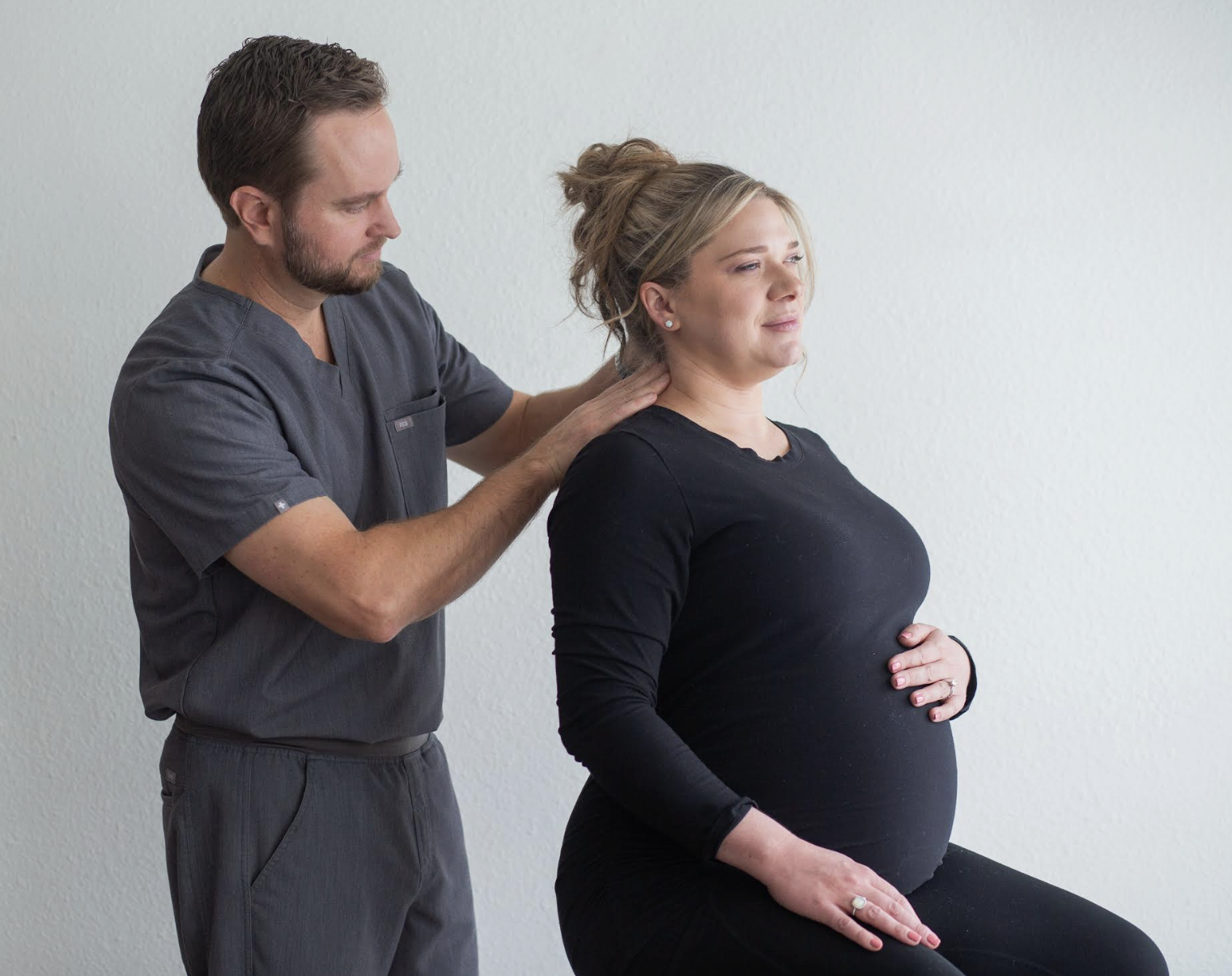 Pregnant woman receiving chiropractic care from a practitioner, focusing on prenatal wellness and relief from pregnancy discomforts in a clinical setting.